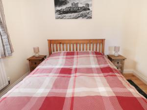 a bed with a red and white plaid blanket on it at Breamish in Longframlington