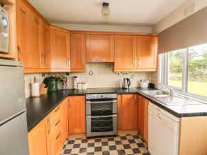 uma cozinha com armários de madeira e um forno com placa de fogão em Findale em Wexford