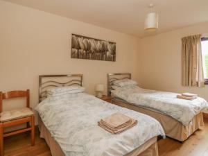 a bedroom with two beds and a chair and a window at Burnside Lodge Lodge 1, Glengoulandie in Aberfeldy