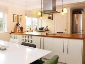 a kitchen with white cabinets and a wooden counter top at Cable House in Cemaes Bay
