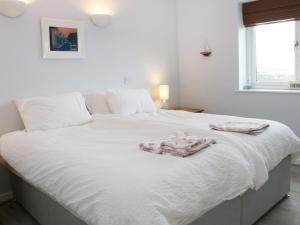 Una cama blanca con dos toallas encima. en Cable House en Cemaes Bay