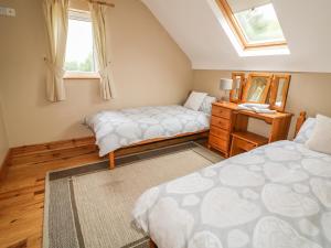 a bedroom with two beds and a mirror at Kate's Cottage in Rathmullan