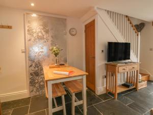 a living room with a table and a tv on a wall at Crift Farm Cottage in Bodmin