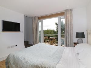 um quarto com uma cama e uma grande janela em Crift Farm Cottage em Bodmin