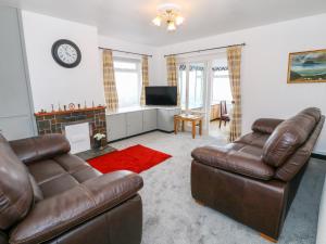 a living room with two leather couches and a television at Dalar Deg in Rhiw