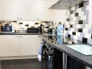 a kitchen with white cabinets and a counter top at Dalar Deg in Rhiw