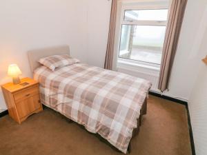 a small bedroom with a bed and a window at Dalar Deg in Rhiw