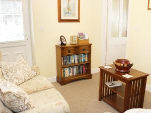 sala de estar con sofá y estante para libros en Highbury Cottage, en Shrewsbury
