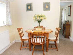 a dining room table with chairs and a vase of flowers at Highbury Cottage in Shrewsbury