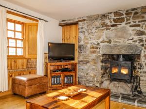 a living room with a stone wall with a wood stove at 83 Seatown in Buckie