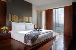 a bedroom with a large bed and a large window at Hansar Bangkok Hotel in Bangkok