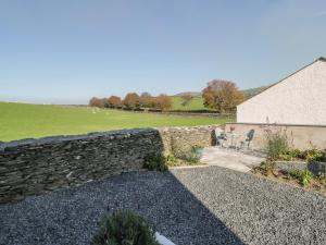 uma parede de pedra ao lado de um campo e um edifício em Yew Fold em Soutergate