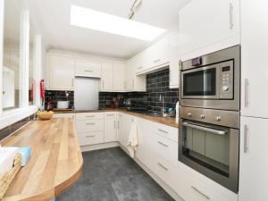 a kitchen with white cabinets and a wooden table at Garden Cottage in Perth