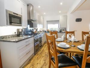 a kitchen with a wooden table and a dining room at Garth Cottage in Denbigh