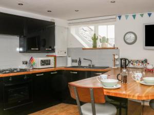 a kitchen with black cabinets and a wooden table at The Compass in Swanage