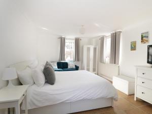 a white bedroom with a white bed and a blue couch at 20 Ulwell Road in Swanage