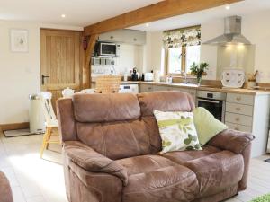 a living room with a brown couch in a kitchen at Acorn Cottage in Ludlow