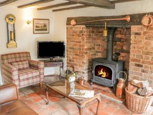 sala de estar con chimenea y TV en Little Pound House en Mamble