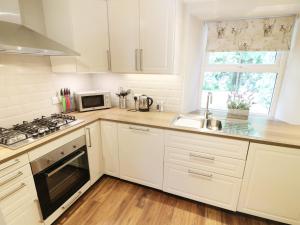 una cucina con armadi bianchi, lavandino e piano cottura di Shepherd's Crook ad Ambleside
