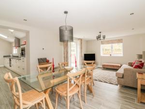 a dining room and living room with a glass table and chairs at Greenacres in Norwich