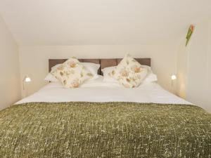ein Bett mit einer grünen Decke und Kissen darauf in der Unterkunft Yew Court Cottage in Scarborough