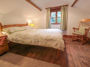 a bedroom with a bed and a chair and a window at Happy Cow in Coleford