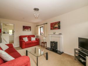 a living room with a red couch and a tv at Lowbrook Cottage in Diss