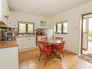 a kitchen with a wooden table and chairs at Lowbrook Cottage in Diss