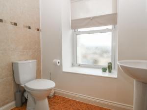 a bathroom with a toilet and a sink and a window at Cottage 1 Newcourt in Torquay