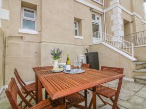 a wooden table with a bottle of wine and chairs at Cottage 1 Newcourt in Torquay