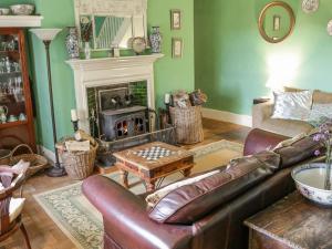 a living room with a leather couch and a fireplace at Garfield House in South Brent