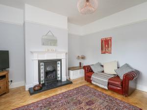 a living room with a red couch and a fireplace at Sunlight Soap Cottage in Wirral