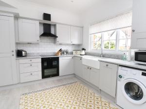 a kitchen with white cabinets and a washer and dryer at Sunlight Soap Cottage in Wirral