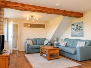 a living room with two blue couches and a table at Rose Cottage in Barnstaple