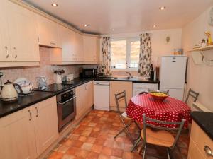 een keuken met witte kasten en een tafel met een rode tafellaken bij Fishermans Cottage in Saltburn-by-the-Sea