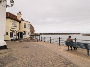 Ein Mann, der auf einer Bank sitzt und auf das Wasser schaut. in der Unterkunft Fishermans Cottage in Saltburn-by-the-Sea + 14 Fotos