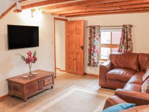 a living room with a couch and a tv at Old Hall Barn 4 in Church Stretton