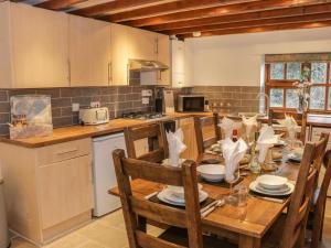 a kitchen with a wooden table with chairs and a tableablish at Old Hall Barn 4 in Church Stretton