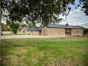 a large stone house with a large yard at Lower Farm Barn in Oxford