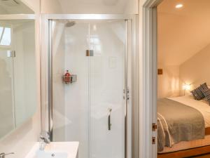 a bathroom with a shower and a sink and a bed at Lantern Cottage in Padstow +17 photos
