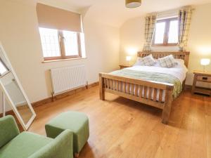 a bedroom with a bed and two chairs and two windows at Ty Berllan in Caersws