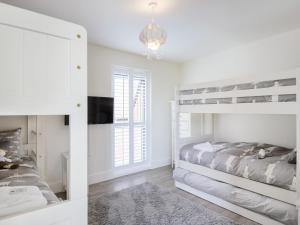 a bedroom with two bunk beds and a tv at Restharrow Lodge in Bamburgh