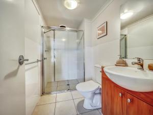 a bathroom with a shower and a sink and a toilet at Seachange Apartments Merimbula in Merimbula +25 photos