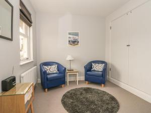 a living room with two blue chairs and a table at Swan Cottage in Arundel