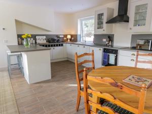 a kitchen with white cabinets and a wooden table at Fois House in Aberfoyle