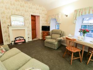 ein Wohnzimmer mit einer Couch, einem Tisch und einem Kamin in der Unterkunft Garden Cottage in Castle Douglas