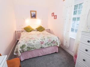a bedroom with a bed with a floral bedspread at Garden Cottage in Castle Douglas