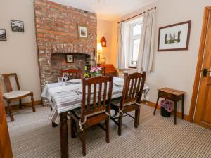 a dining room with a table and a brick fireplace at Chapel Cottage in Filey