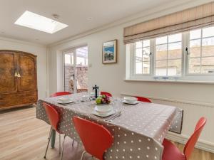 a dining room with a table and red chairs at Long Barn in Burton Bradstock