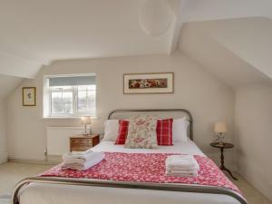 a bedroom with a large bed with red pillows at Long Barn in Burton Bradstock